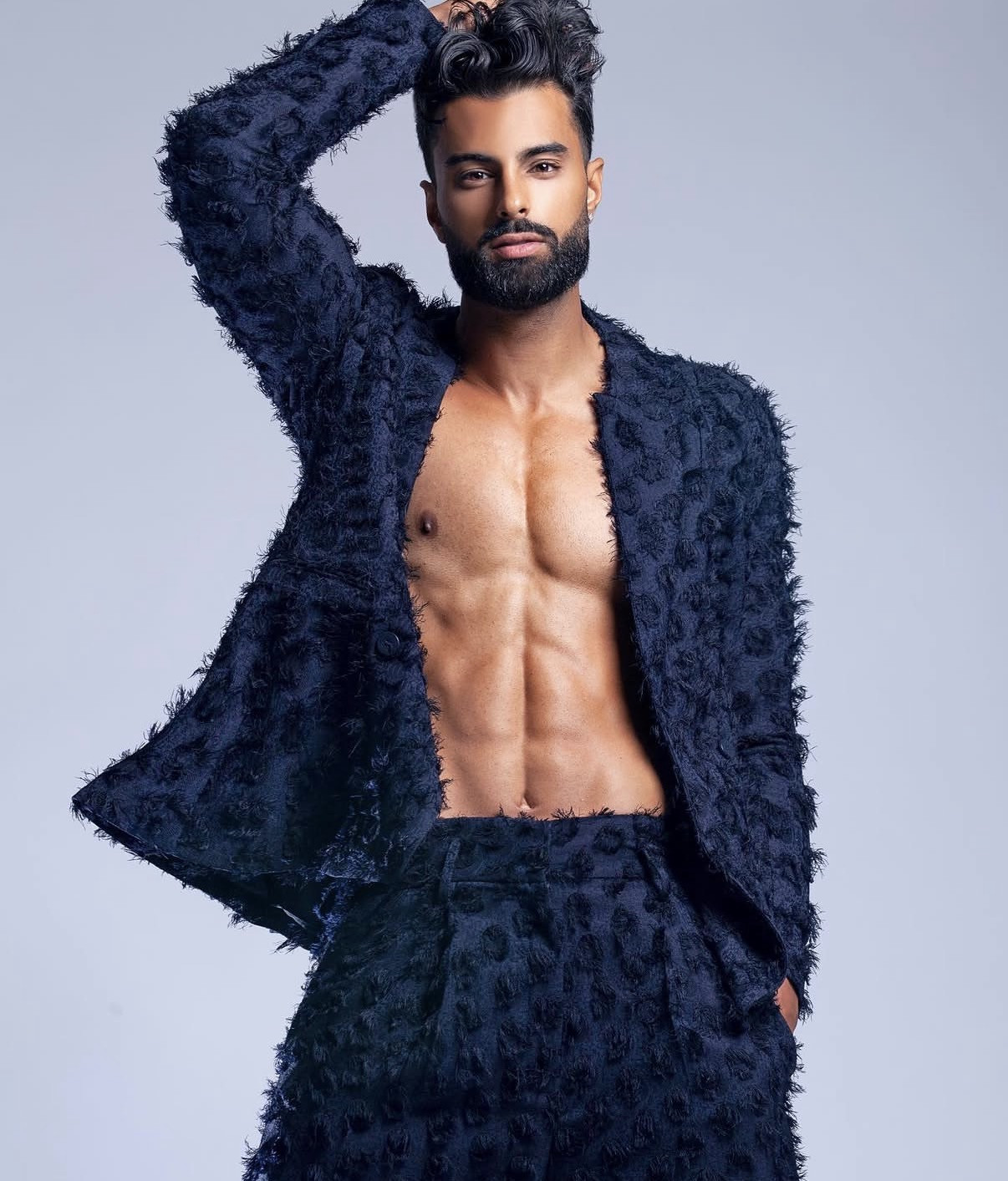 Harry Johal in a textured navy suit against a pale studio backdrop.