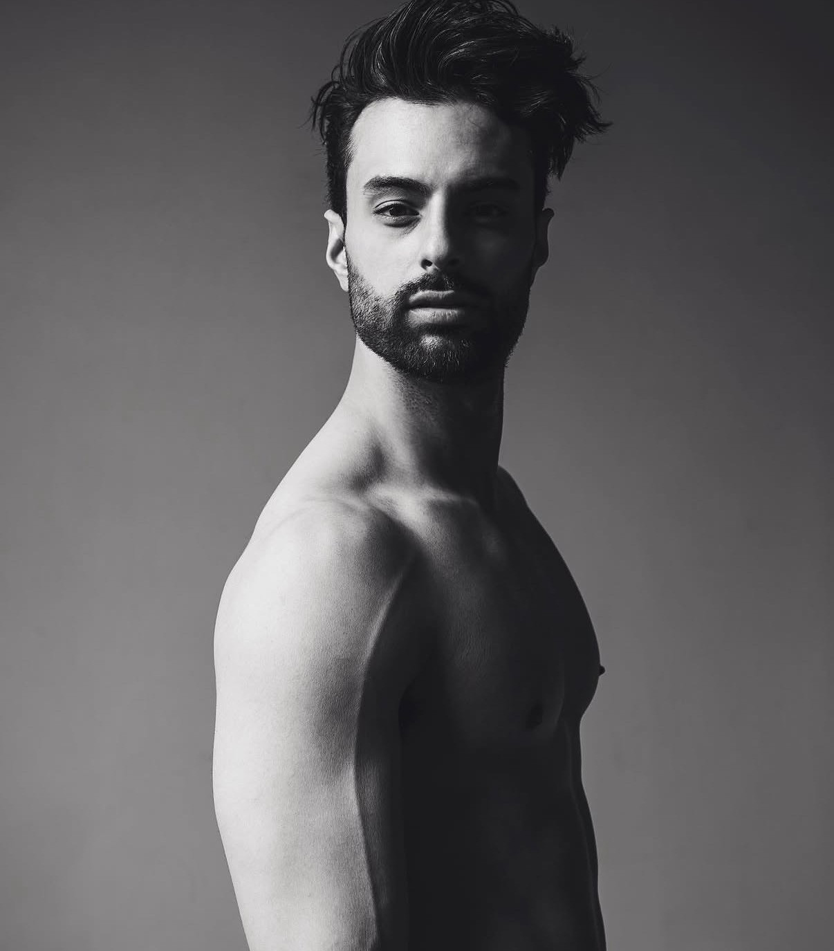 Black and white studio portrait of Harry Johal in profile against a grey backdrop.