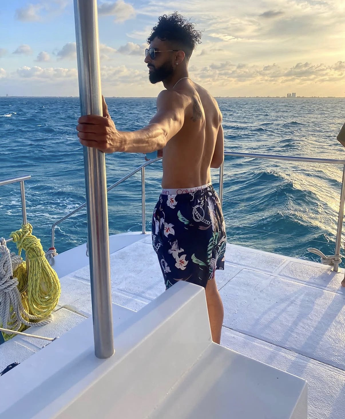 Harry Johal on the deck of a boat at golden hour, open ocean behind him.
